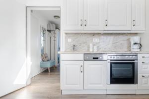 a white kitchen with white cabinets and a stove at Lister Wind in List