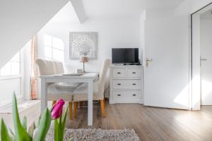 een witte eetkamer met een tafel en een tv bij Lister Wind in List