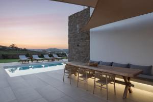 a patio with a wooden table and chairs next to a pool at Retreat Hill Luxury Villas Mykonos in Mýkonos City +28 photos