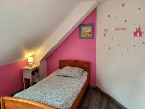 - une chambre avec un lit et un mur rose dans l'établissement Maison terre et bord de mer, à Lessay