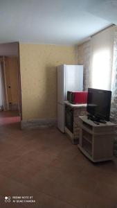 a kitchen with a refrigerator and a table with a tv at Open Space da Luca e Laura,a 7 minuti da Alghero. in Olmedo