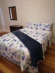um quarto com uma cama com um cobertor estampado de flores em Jerusalem Backpackers em Cidade do Cabo