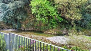 a fence next to a river with trees and plants at Nanin's Home in Sori