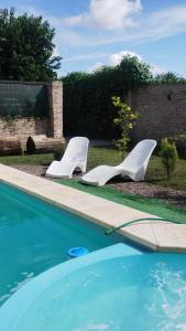 twee witte stoelen naast een zwembad bij La Casita Quincho in González Catán