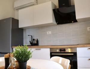 uma cozinha com armários brancos e uma mesa com uma planta em Sol Insula em Murter