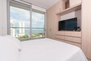 a bedroom with a white bed and a large window at Beachside Bliss: Salguero Suites in Gaira
