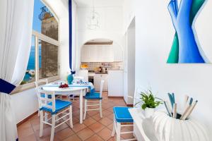 une cuisine avec une table blanche et des chaises bleues dans l'établissement Casa Mimosa, à Positano
