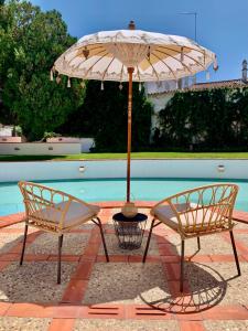 dwa krzesła i parasol obok basenu w obiekcie Casa Pitta Charm Villa w mieście Santarém