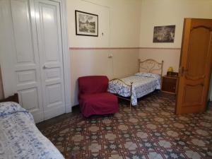 een slaapkamer met een bed en een rode stoel bij Gatti al Borgo in Catania