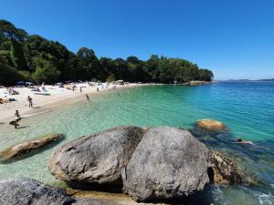 a group of people on a beach with rocks in the water at Pura Playa - Cangas do Morrazo - Primera línea de playa - Rías Baixas - Galicia in Cangas de Morrazo