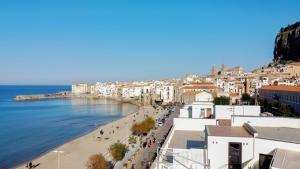 una vista di una spiaggia con edifici e l'oceano di Suites di Costanza a Cefalù