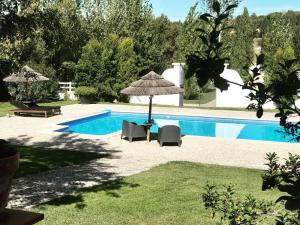 a pool with chairs and an umbrella and a table and chairs at Casa Pitta Charm Villa in Santarém