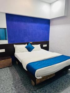 a bedroom with a large bed with a blue wall at HOTEL SHREE DWARKA in Dwarka