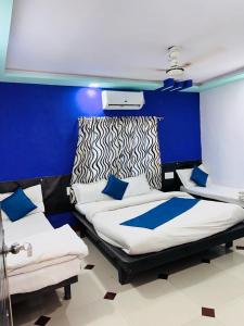 Duas camas num quarto com uma parede azul em HOTEL SHREE DWARKA em Dwarka