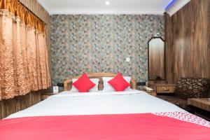 a bedroom with a large bed with red pillows at Super Capital O Hotel Bidisha in Digha