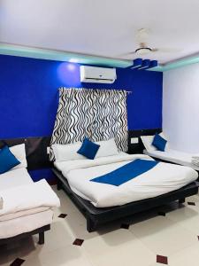 a bedroom with two beds and a blue wall at HOTEL SHREE DWARKA in Dwarka