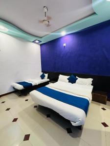 a bedroom with two beds and a blue wall at HOTEL SHREE DWARKA in Dwarka