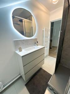 uma casa de banho branca com um lavatório e um espelho em Charmant studio proche de la gare em Rambouillet