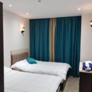 1 dormitorio con 2 camas y cortinas azules en ميراج باي (شاليه) en Hurghada