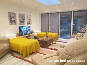 sala de estar con 2 camas y manta amarilla en New - Spacious London 1 bedroom king bed apartment in quiet street near parks 1072gar, en Londres