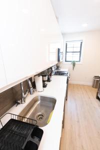 a kitchen with white counters and a sink at Stylish luxe apartment close to New york city in Union City