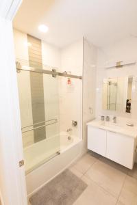 a white bathroom with a shower and a sink at Stylish luxe apartment close to New york city in Union City