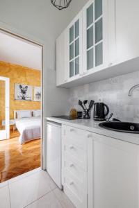 uma cozinha branca com um lavatório e um quarto em Apartment Stay em Novi Sad