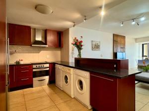 een keuken met een wasmachine en droger. bij Loddey's Self Catering Apartments - by Beach Collection in Strand