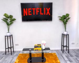 a living room with a table and a netflix sign on the wall at I Love London! A Stunning 2 Bed Home Sleeps 1-3! in London