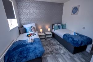 two beds in a room with blue sheets and candles at I Love London! A Stunning 2 Bed Home Sleeps 1-3! in London