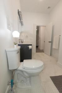 a white bathroom with a toilet and a sink at Mins to NYC - Lavish modern 2-bed apartment in Bayonne