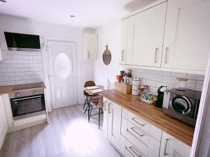 a kitchen with white cabinets and a microwave at Entire 3-Bedroom Home in Oldham - Guest house in Oldham