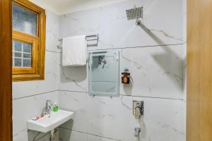 a white bathroom with a sink and a mirror at Premium 2bhk near Airport, Manipal Hospital, Venkatesh Hospital and Yashobhoomi Convention Centre in New Delhi