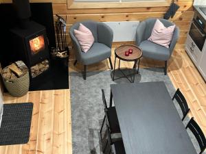 sala de estar con 2 sillas, mesa y chimenea en Norra Skoga Bergvik, en Ekshärad