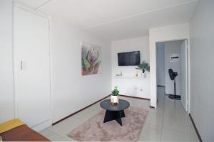 een witte woonkamer met een tafel en een tv bij Madison Palms apartment in Sandown in Johannesburg