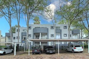 een wit gebouw met auto's ervoor geparkeerd bij Madison Palms apartment in Sandown in Johannesburg