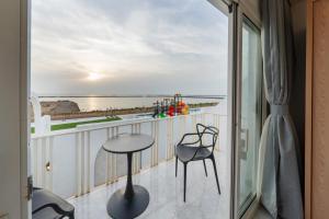 balcón con mesa, sillas y vistas al océano en شاليهات شاطىء غروب الشمس لبيوت العطلات en Jazán