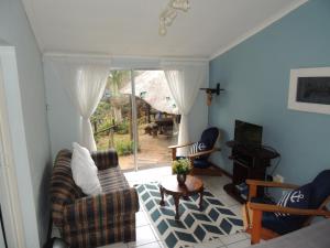 a living room with a couch and chairs and a television at Woodgrange Garden Cottages in Hibberdene