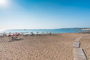 a beach with umbrellas and people sitting on the sand at Alios apartment in Rhodes Town