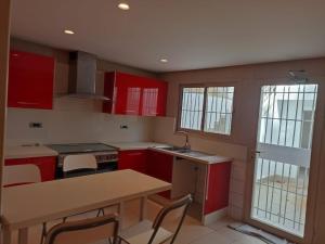 uma cozinha com armários vermelhos, uma mesa e cadeiras em La Fondation em El Harhoura