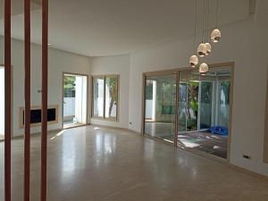 an empty living room with glass doors and a chandelier at La Fondation in El Harhoura