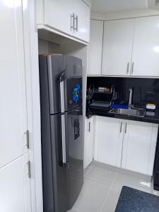a kitchen with a stainless steel refrigerator and white cabinets at Cómodo y acogedor apartamento in Mendoza