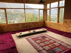 Cette chambre dispose d'une grande fenêtre et d'un tapis au sol. dans l'établissement Hunza Verse Luxury Home stay, à Hunza
