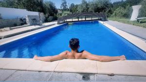 a man is sitting in a swimming pool at QUINTA FENIX - Studio familial avec cuisine in Cerejeiras