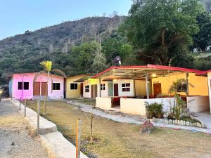 a row of colorful houses in front of a mountain at Shivanjal River Resort in Bijni