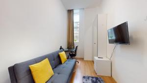 uma sala de estar com um sofá cinzento e almofadas amarelas em Small & Cosy 1 Bedroom Flat em Londres