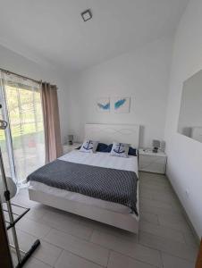 een witte slaapkamer met een bed en een raam bij Oceanus in Faja Grande
