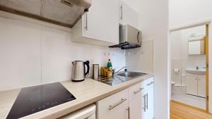 uma cozinha com armários brancos e um lavatório em Small & Cosy 1 Bedroom Flat em Londres
