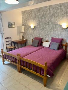 a bedroom with a large bed with purple sheets at Gîte Ensemont in Saramon +12 photos