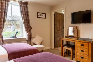 a bedroom with a bed and a desk with a television at Bridgend House B&B in Drumnadrochit
